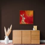 “Hare, Dryer…” presents a serene portrait of a hare at dawn, bathed in the soft warmth of a rising sun. Set against rich tones of red, yellow, and marigold, the hare rests calmly among oversized, abstracted flowers — a quietly radiant scene that speaks of warmth, stillness, and gentle renewal. Painted by renowned UK wildlife artist Ann Richmond, the artwork comes alive with vibrant brush strokes over a richly textured canvas, capturing the delicate interplay of nature in a moment of quiet wonder. Each piece in The Wylde Ones is rendered in Richmond’s fresh, energetic, and gestural new style—a deliberate departure from her works in The Otherwurlde Collection. The backgrounds are carefully matched to hues from a heritage palette we affectionately call “Barrow & Fall”; complementing these striking and distinctive portrayals of British wildlife. Discover the original works and fine-art prints at Otherwurlde.com.