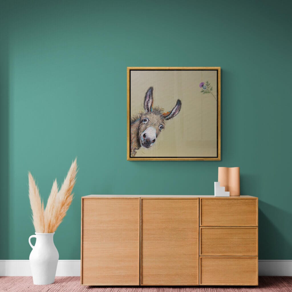 "You Called?" painted by renowned UK wildlife artist Ann Richmond, is a whimsical portrait featuring a donkey that's leaning into the painting, as if just noticing us. Or has it noticed that thistle? The piece comes alive with vibrant brush strokes over a richly textured canvas, capturing the delicate interplay of nature in a moment of quiet wonder. Each piece in The Wylde Ones is rendered in Richmond’s fresh, energetic, and gestural new style—a deliberate departure from her works in The Otherwurlde Collection. The backgrounds are carefully matched to hues from a heritage palette we affectionately call “Barrow & Fall”; complementing these striking and distinctive portrayals of British wildlife. Discover the original works and fine-art prints at Otherwurlde.com.